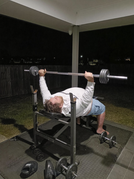 Xavier lifting weights on a bench press at home